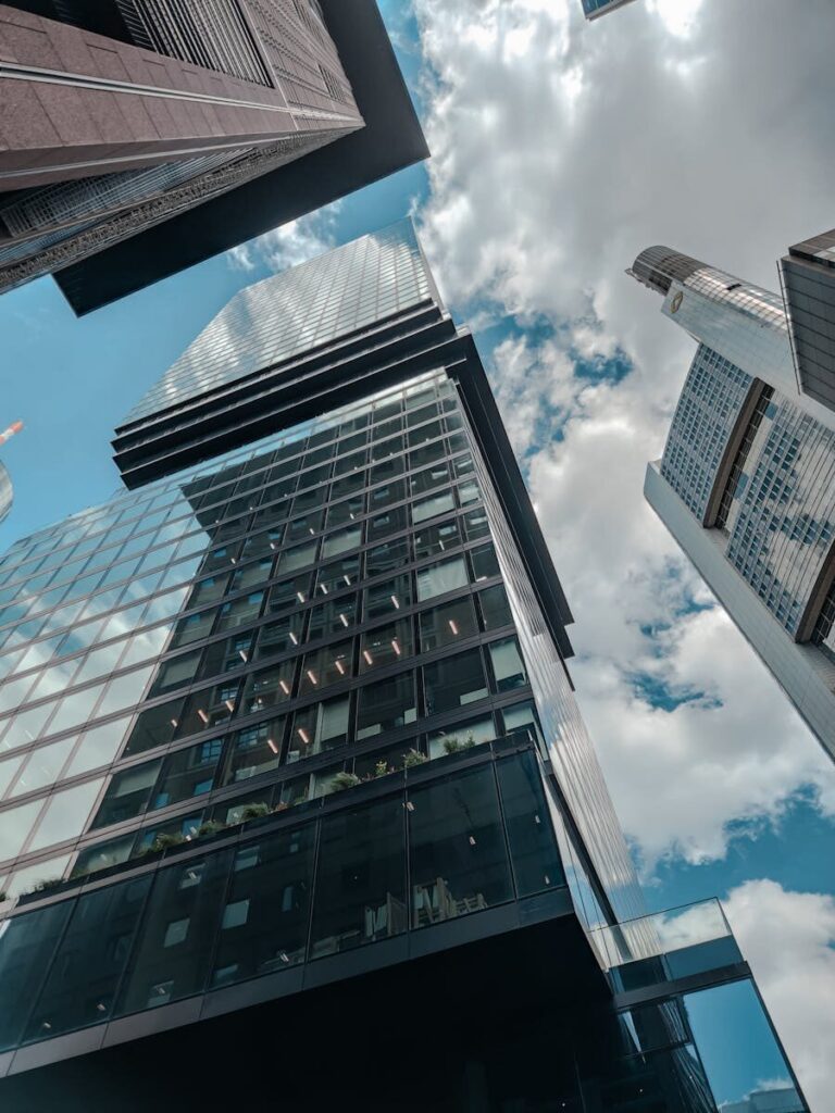 Low-angle shot of high-rise buildings reaching into a cloudy blue sky, showcasing modern architecture.